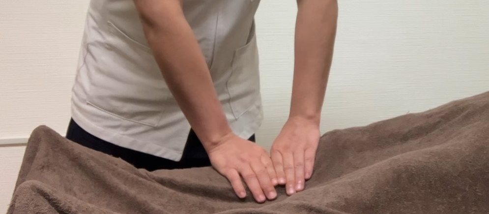 観音指圧の施術風景。院長が両手で背中を押さえている