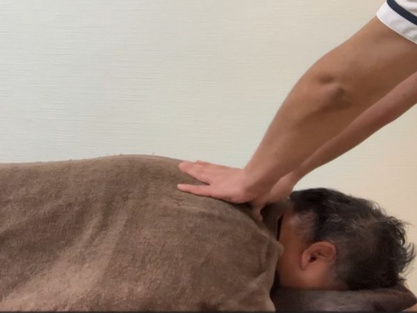 肩甲骨のあたりを押さえている施術風景